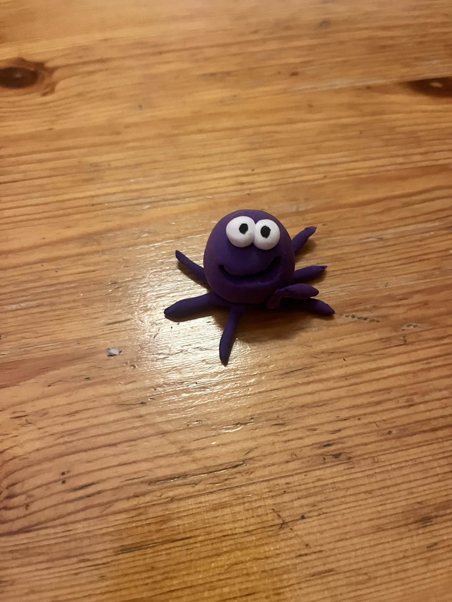 Lila Mini-Squig mit acht Beinen auf Holzboden